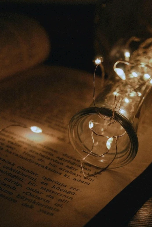 two mason jar lights, some with string lights, on an open book