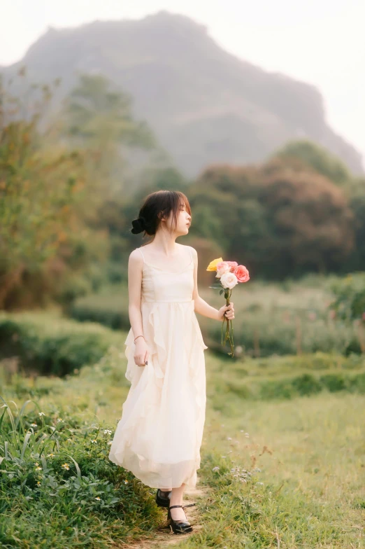 a woman in white dress walking down a path with flowers