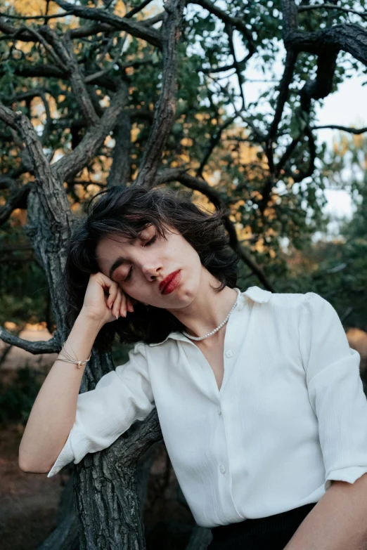 a woman sitting on top of a tree with her hands behind her head