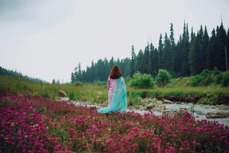 the woman is walking in a field of flowers