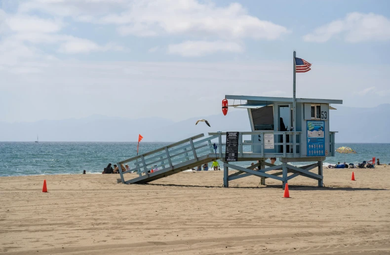 life guard stand on sandy beach with a flagpole and steps leading up to it