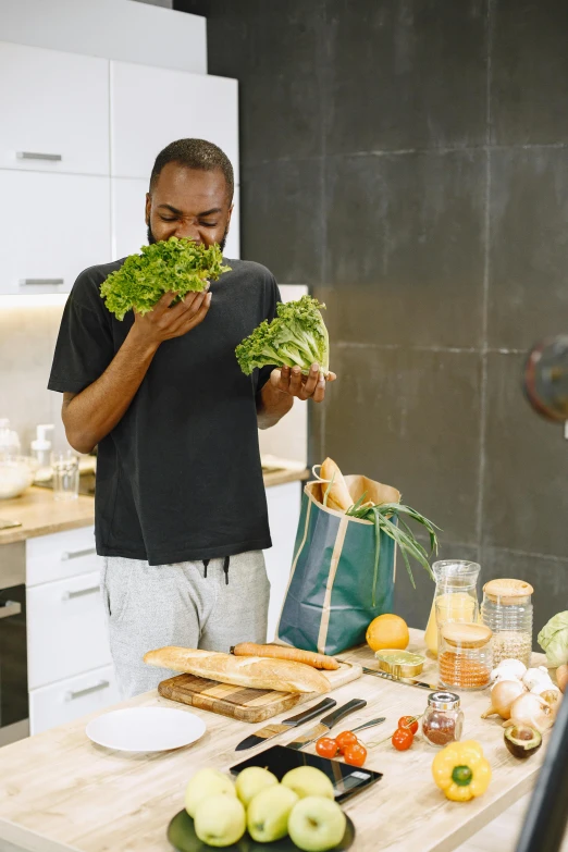 a man holding a big bunch of vegetables on top of a table