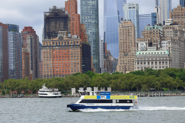 large blue boat on the water next to tall buildings