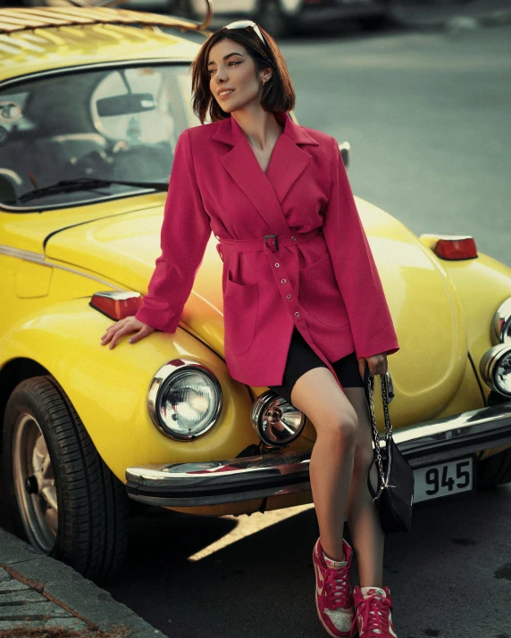 a woman is sitting on the front of an old yellow car