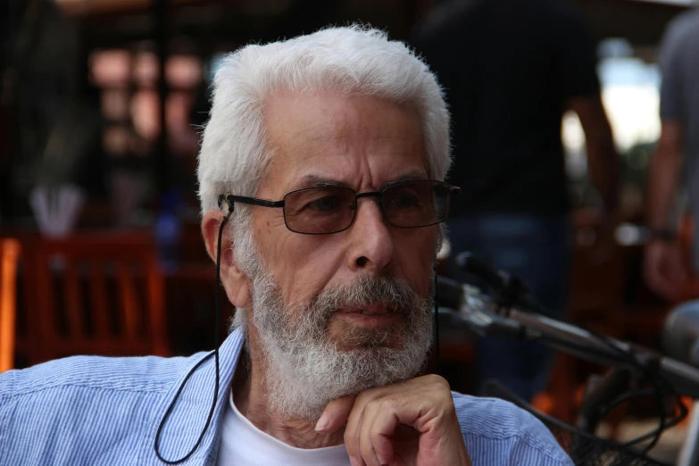 an older man with white hair in glasses looks out