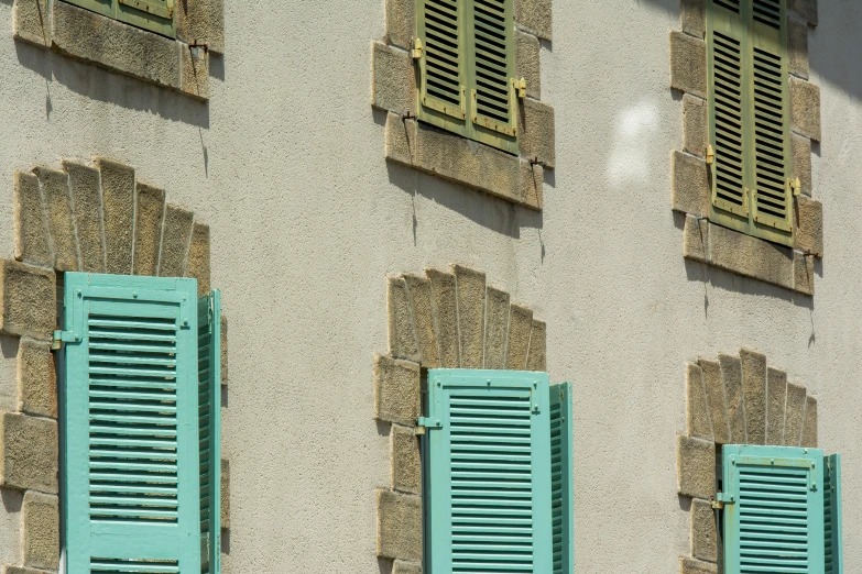 the windows of an old building with some green shutters