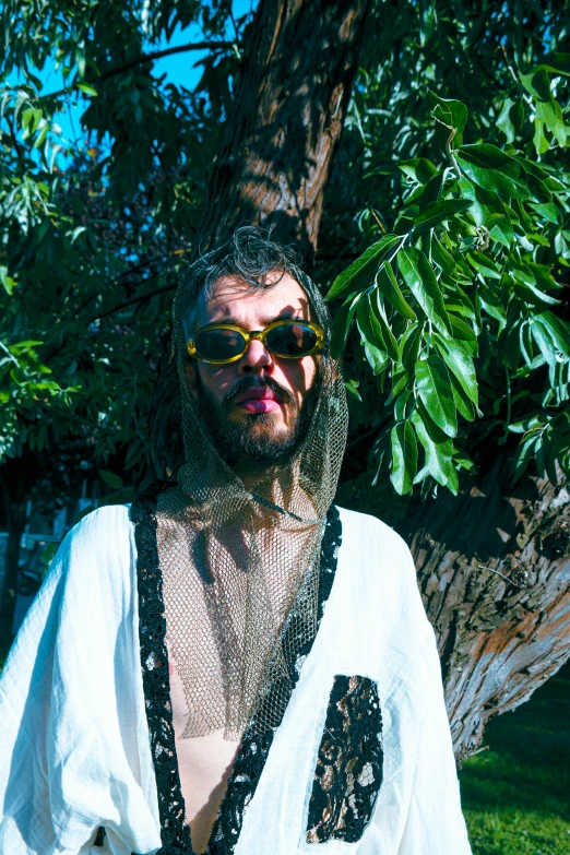 a man standing in front of a tree wearing sunglasses