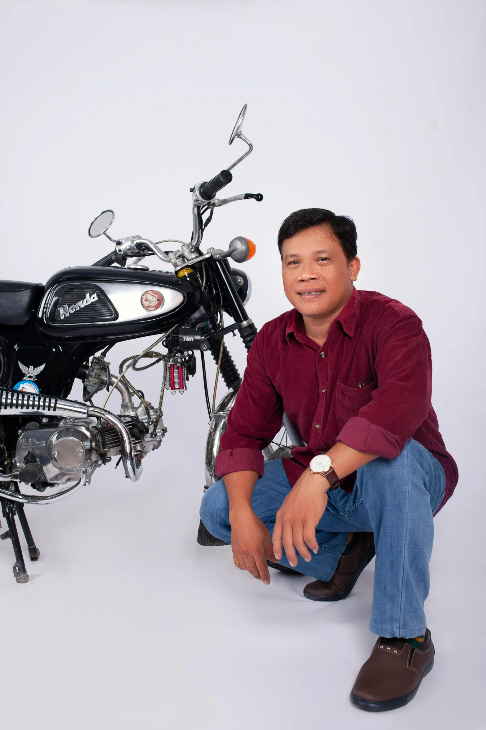 a man squats next to a motorcycle, which is black