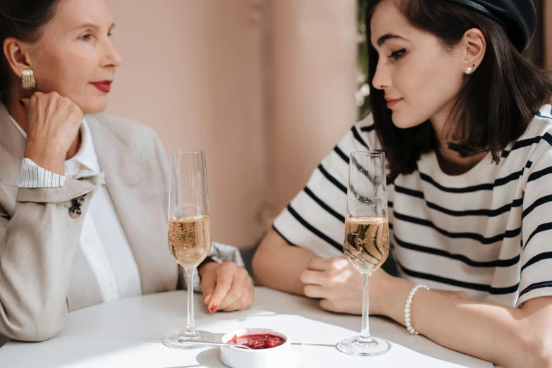 a woman looking at a mirror next to a wine glass