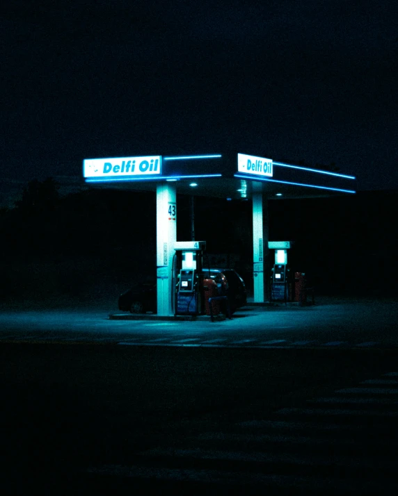 two gas pumps at night lit up by headlights