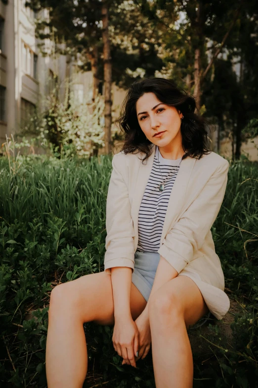 an attractive woman sitting on the grass next to a building