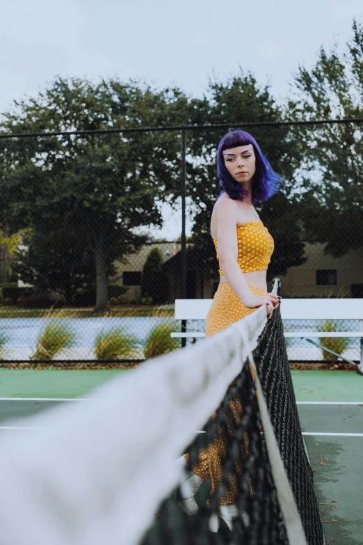 a young woman with purple hair posing on the tennis court