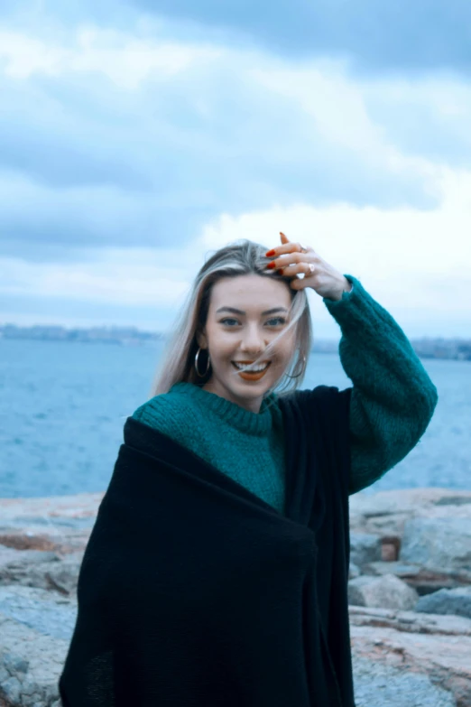 the smiling woman is holding an orange carrot in her hair