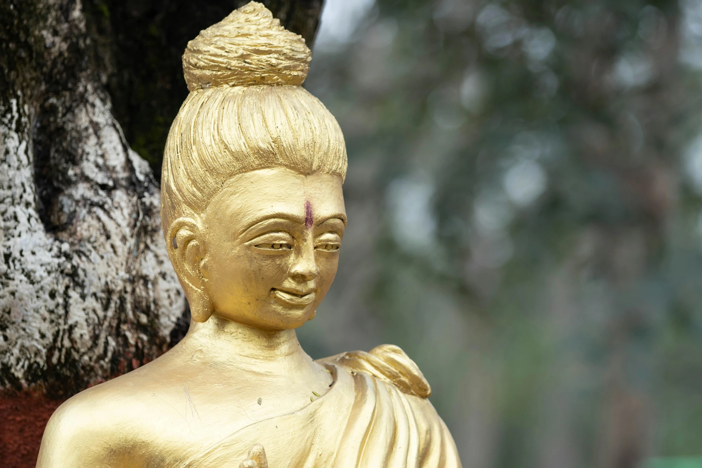 the golden buddha statue is standing in front of the tree