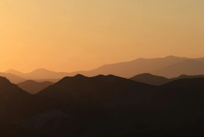 birds fly through the air in front of mountains at sunset