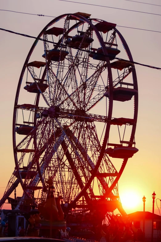 the giant ferris wheel is silhouetted against a setting sun