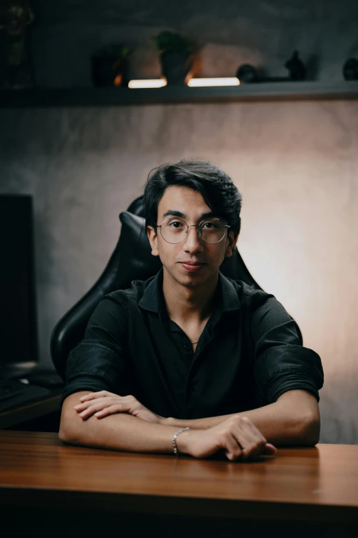 a man in glasses sitting at a desk in front of a computer