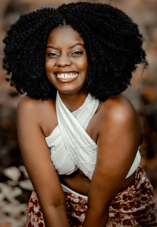 an african woman poses for a portrait while wearing a white tank top and floral skirt