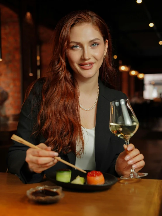 a woman is holding a glass of wine and eating sushi