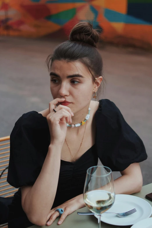 a woman sitting at a table next to a glass of wine