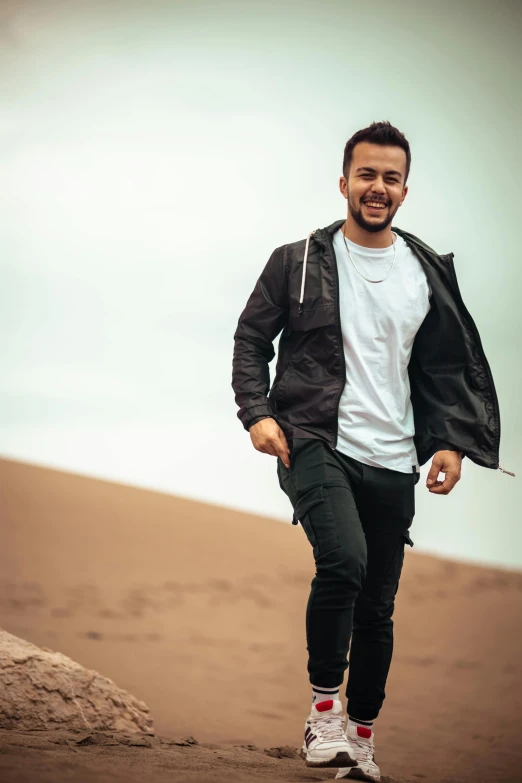 a man wearing a white t - shirt, black and grey jacket and black jeans