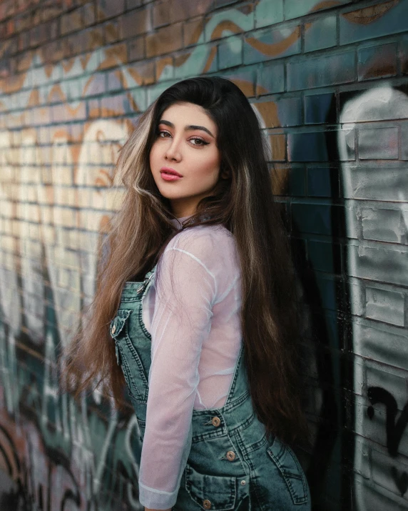 a girl with long hair posing for a portrait against graffiti