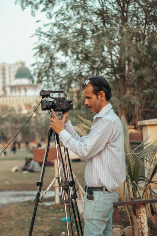 a man is holding an old camera while wearing a white striped shirt