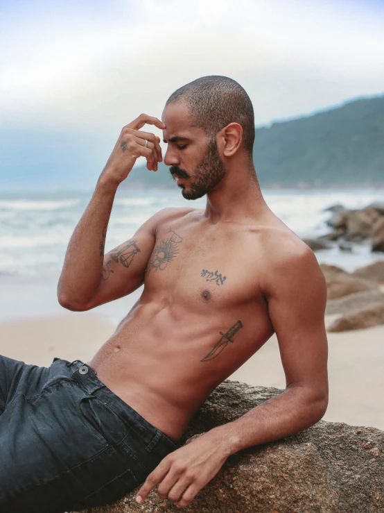 a bald man sits on a rock with his head and eyes to the side