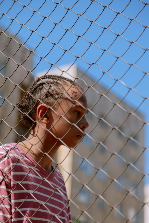 a girl behind a fence looking at soing