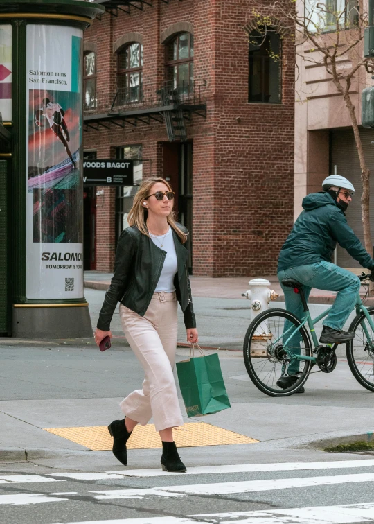 a woman crossing a street with another man crossing the street behind her