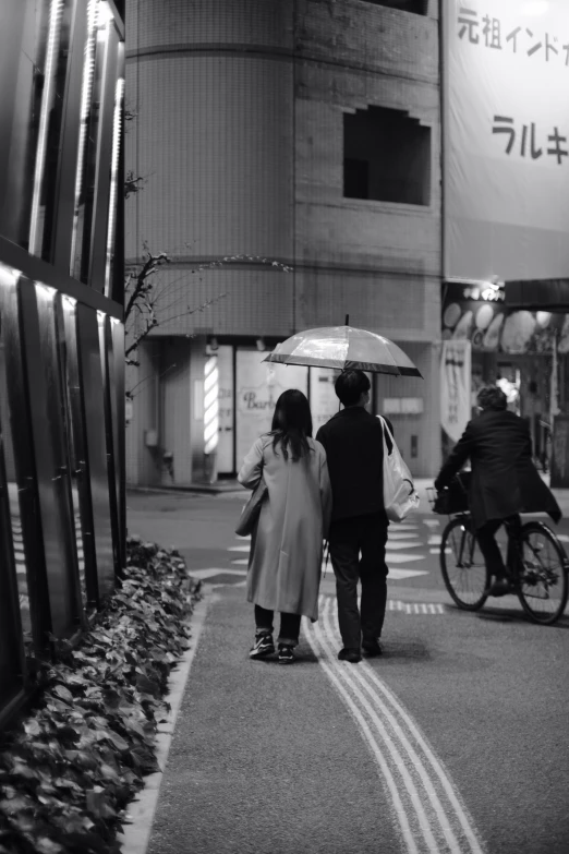 two people walking down the street holding umbrellas