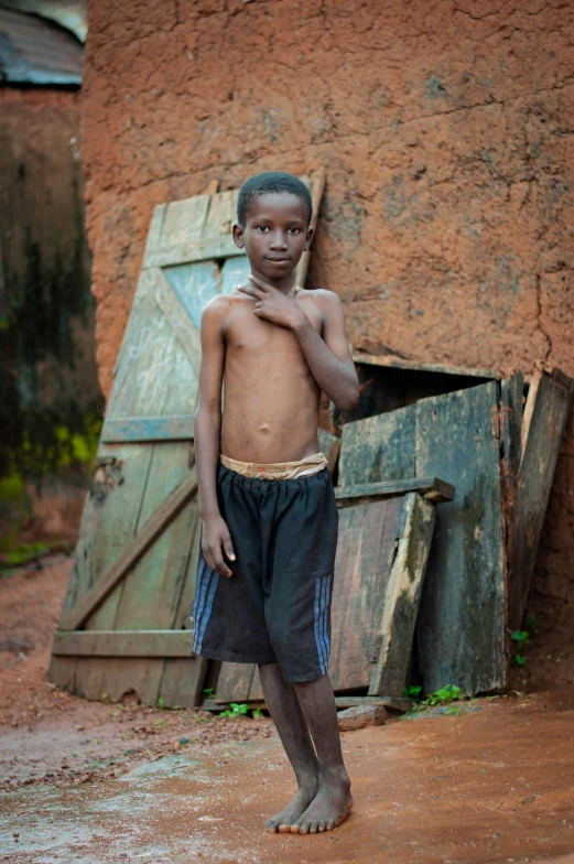 a shirtless  poses in front of a brown building