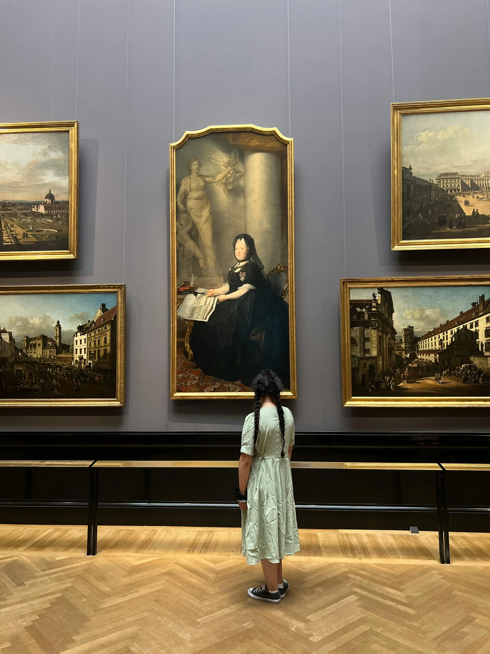 a woman standing next to paintings on display