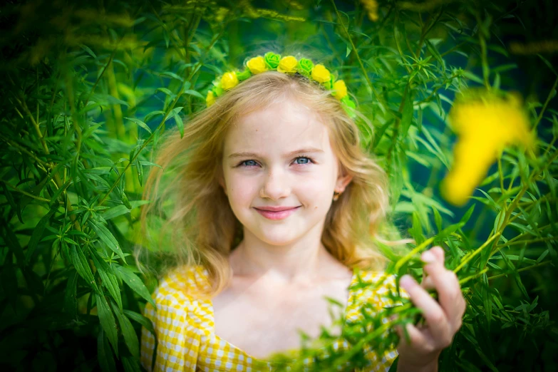 a girl wearing yellow in a field with green grass and flowers