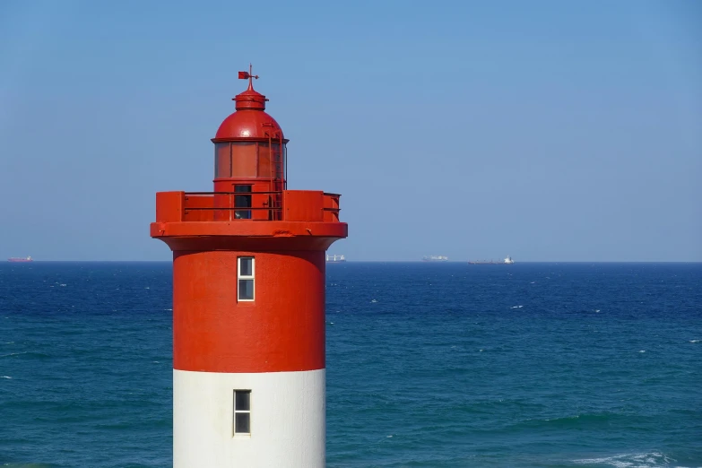 a light house near the beach with blue ocean in the background