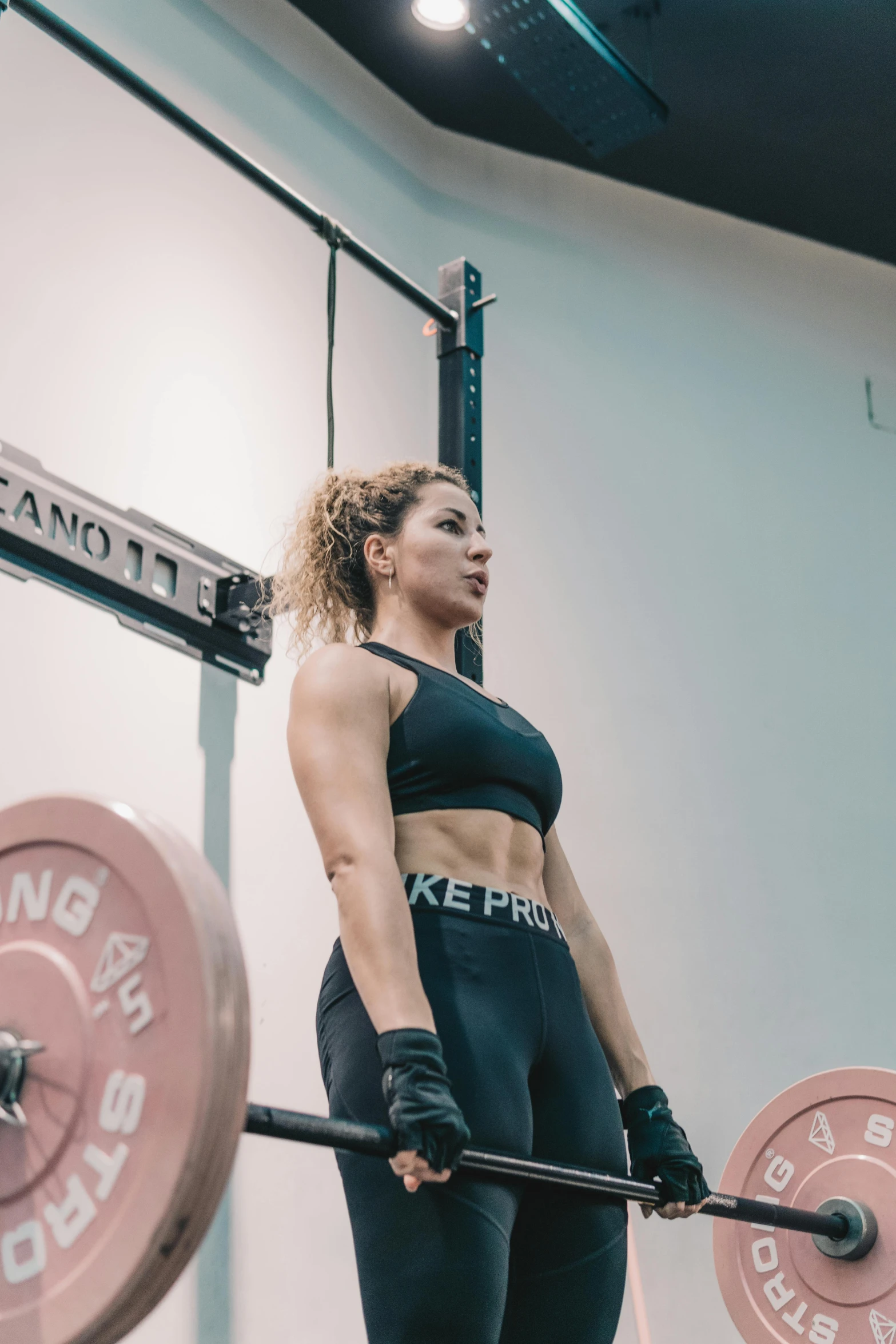 a woman holding a barbell up in the gym