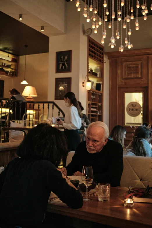 an older man eating in a restaurant next to two other people