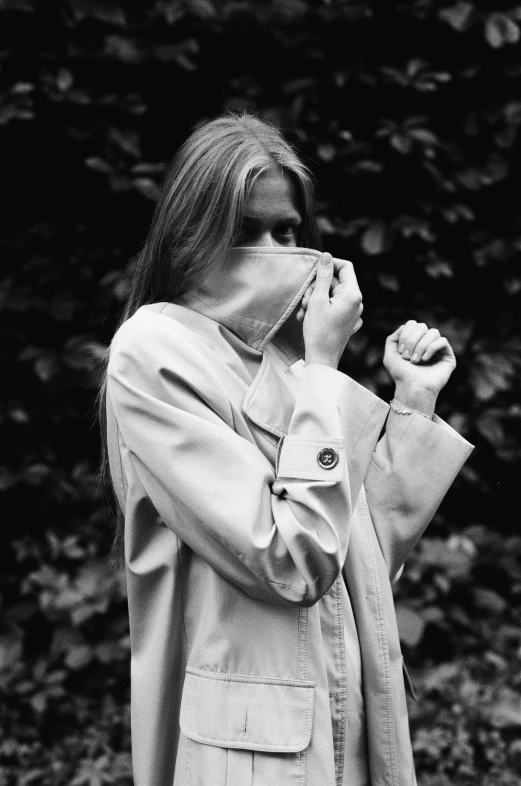 a woman in glasses is holding her nose while standing in front of some bushes