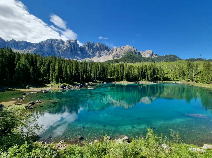 a blue lake surrounded by green trees near some mountains