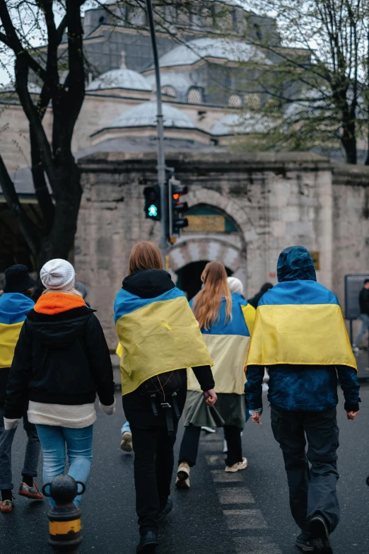 several people walking down a street with coats over them