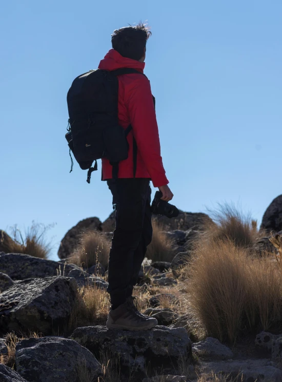 a man with a backpack looks at the view of a mountain