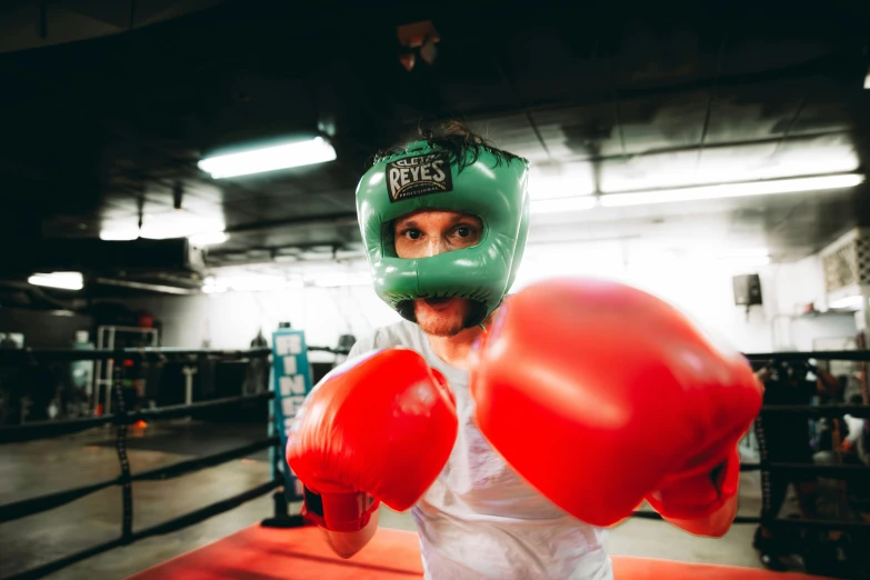 a man wearing red boxing gloves and a green boxing mask