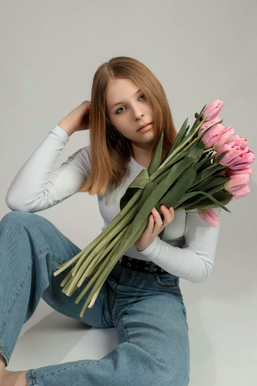 a woman in white shirt holding up a bouquet of flowers