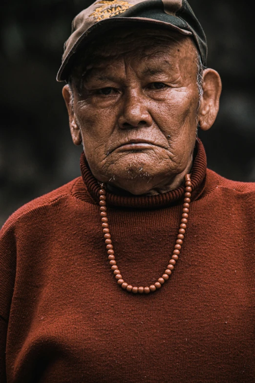 an old man wearing a hat and necklace