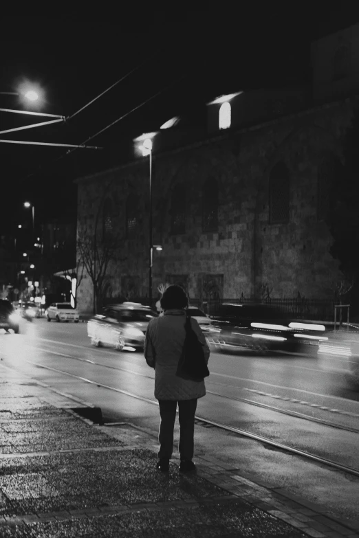 black and white po of a woman standing on the side of the street