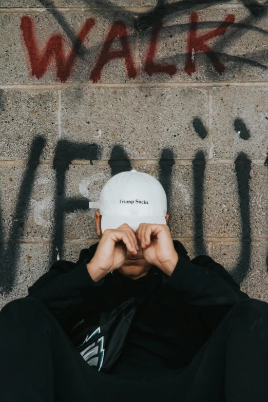 man in front of wall wearing hat with graffiti on it