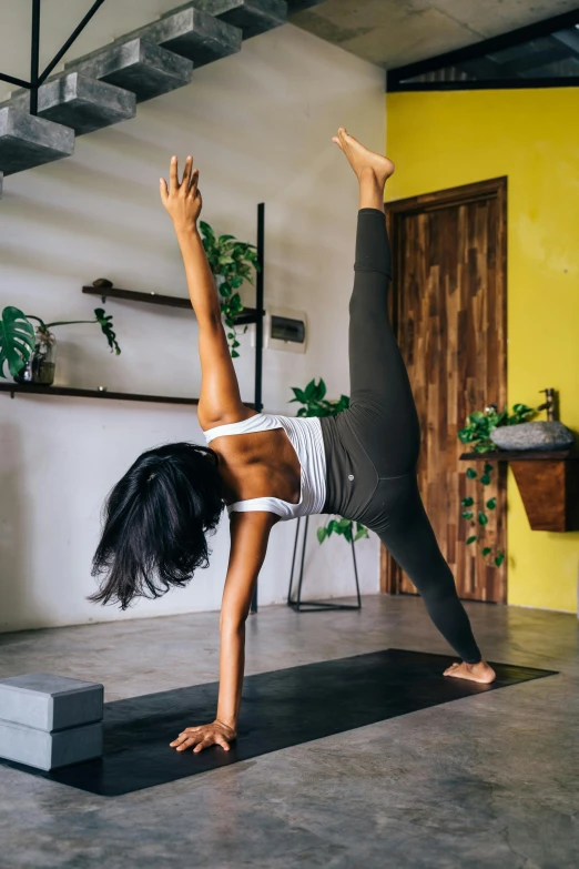 a woman does yoga on a black mat