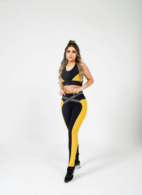 a woman standing in a studio wearing a yellow and black outfit