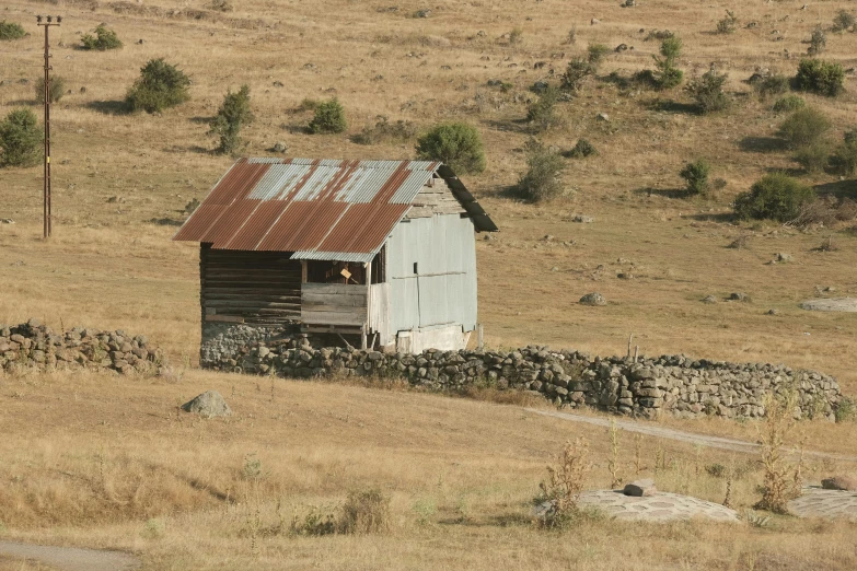 an old building stands on the side of a grassy field