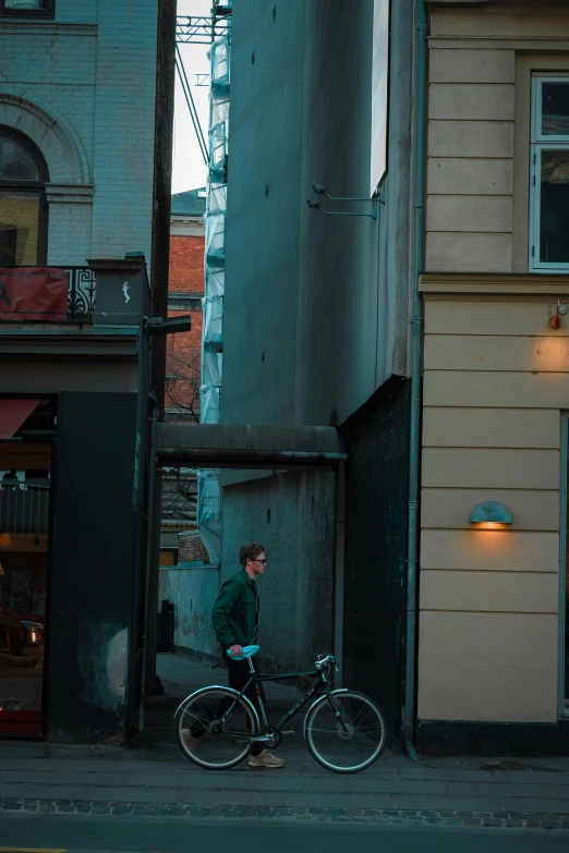 a person walking a bike down a street near a tall building